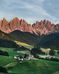 Beautiful village in the Alps. Santa Magdalena on Dolomites Background. Sunset in the mountains in Italy. Red peaks of mountains.