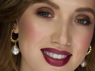 Close-up of the beauty of half a woman's face with creative fashionable make-up of sparkles. Black eyeliner and long eyelashes decorate hazel eyes and lips to match. Well-groomed skin after spa