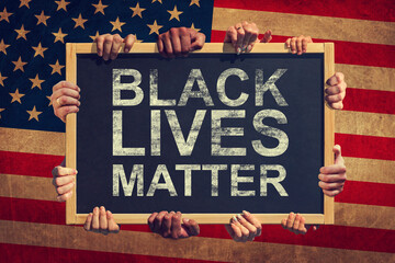 A lot of hand are holding a banner with text BLACK LIVES MATTER on background of American flag....