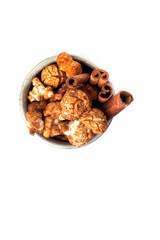 Amazing view of gourmet cinnamon and coffee popcorn with rustic utensils over a white background.