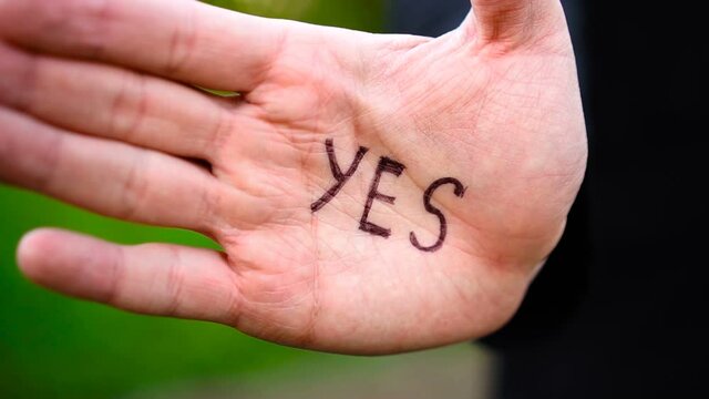 Woman shows palm with the inscription on the palm "Yes"