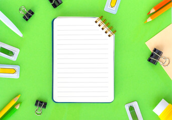 Flat lay with office or school stationery and supplies on bright green background. Top view, copy space. Back to school concept.