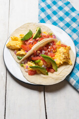 Breakfast egg tacos with flour tortilla and fresh sauce on white background