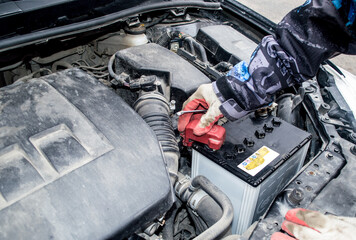 Male hands with gloves set the terminal on the battery