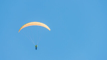 Beautiful paraglider flying in blue sky with copy space for text and smooth background, wide angle