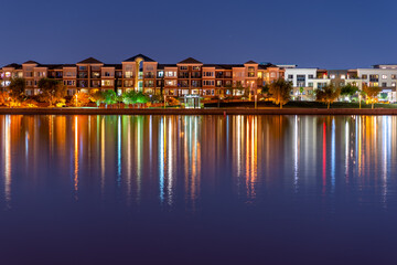 Fototapeta na wymiar The multi-hued lights of stylish condos reflect off the calm waters of Tempe Town Lake in Arizona.