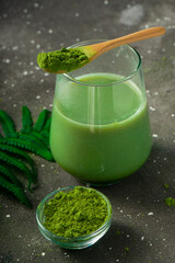 selective focus, Japanese green matcha tea with milk, with a wooden spoon and foliage on a dark background
