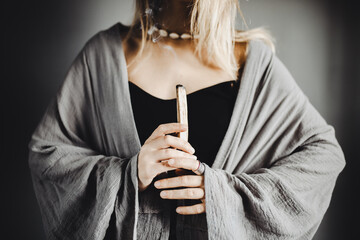 Obraz premium Young boho style woman dressed in grey kimono hold palo santo wood stick 
