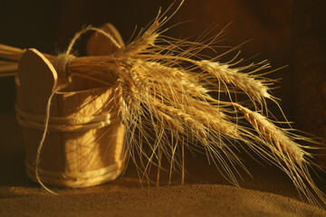 The golden heads wheat ears droop in wooden cask on a brown background.Selected focus.
