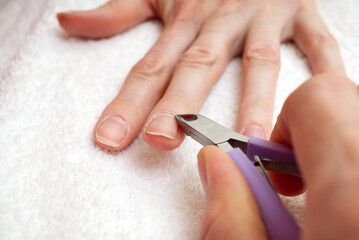 Nail Salon. Manicure process in beauty salon or at home. Closeup Of Female Hand With Healthy Natural Nails Getting Nail Care Procedure. Closeup Hands Removing Cuticles With Professional Nail Tool.