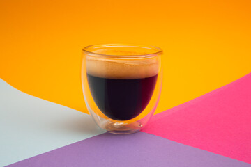Freshly brewed creamy espresso in a glass coffee cup isolated on colorful background, close up with copy space