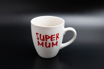 A close up shot of an empty white super mom coffee mug isolated on black background with copy space