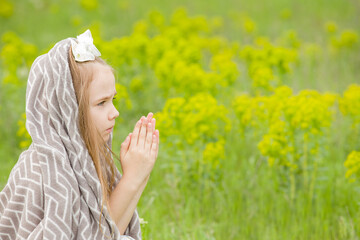 Blonde girl prays to god on green glade
