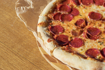 Fragrant classic piperoni pizza in a street cafe is cut into portions. A dish of Italian cuisine.