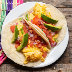 Breakfast egg tacos with flour tortilla and fresh sauce on wooden background
