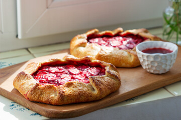 Whole grain flour cake stuffed with strawberries with honey sauce on the windowsill.