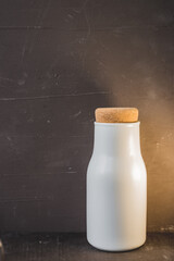 White bottle with milk on dark background/White bottle with milk on dark background with copyspace