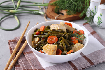Fried chicken with garlic arrows, carrots and soy sauce in a white plate on a gray concrete background, horizontal format