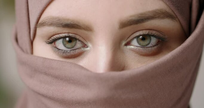 Extreme close up shot of face of beautiful muslim girl in hijab head scarf with natural make up sensually looking at camera - beauty, islam concept 4k footage