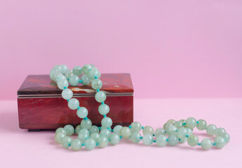 green agate necklace on a gem stone jewelry box on pink background