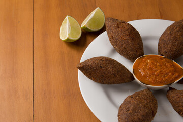 fried kibbeh served with pepper sauce, on a white plate.close up
