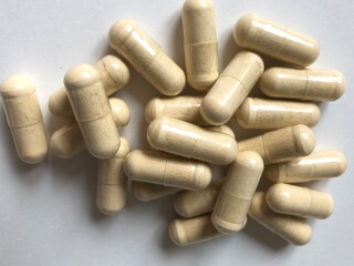 A handful of several capsules containing vitamins or a beige medicine lying on a light background