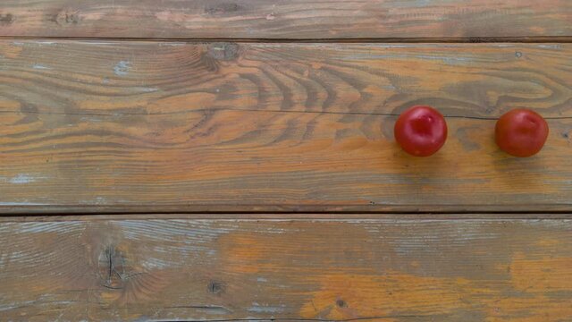 Stop motion animation line of tomatoes moving from left to right on wooden table. 
Group of fresh raw vegetables.