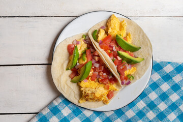 Breakfast egg tacos with flour tortilla and fresh sauce on white background