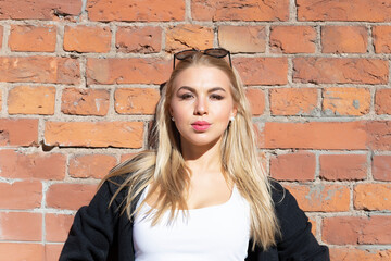 Beautiful blonde posing against a red brick wall