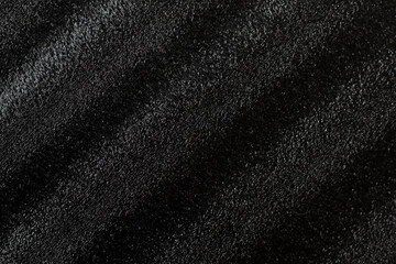 Black plastic material with sloping lines. Background or texture