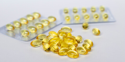 Yellow transparent pills in clear plastic blisters and capsules are on the table on white background. Selective focus. Medical concept.