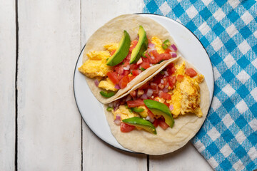 Breakfast egg tacos with flour tortilla and fresh sauce on white background