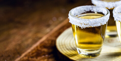 Tequila shot with lemon and sea salt on wooden background, selected focus