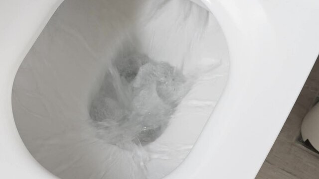 White toilet bowl in a bathroom. Closeup. Flush away water. Nobody