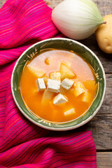 Mexican potato soup with panela cheese on wooden background
