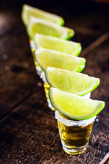 tequila glasses lined up, with tequila, lemon and salt. typical drink from mexico, celebrated...