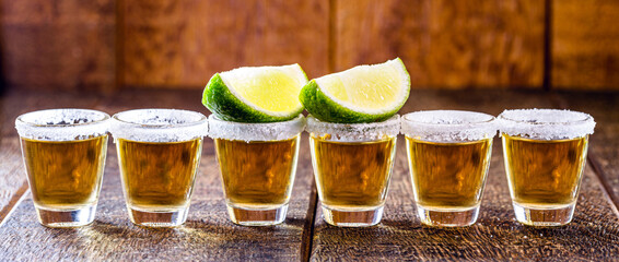tequila glasses lined up, with tequila, lemon and salt. typical drink from mexico, celebrated internationally on the 24th of july. Tequila day.