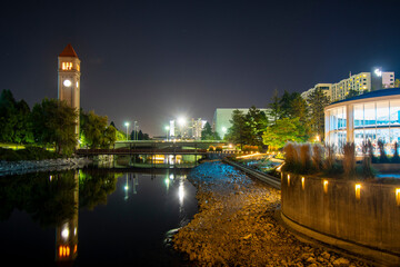 The Clock Tower illuminated next to the Spokane River and carousel in the Riverfront Park area of downtown Spokane, Washington, USA late at night.