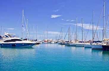 Fototapeta premium Yachts and speed boats at harbor. Yachts moored in the port. Ocean Coast pier. High class lifestyle. Yachting. Expensive toys. Sea ​​transport. Nautical. Yachting sport. Expensive yachts at the pier.