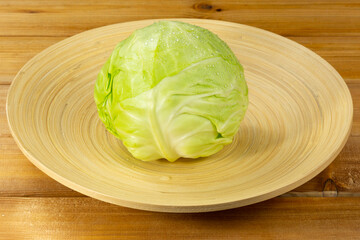 Bamboo plate with head of cabbage on wooden background