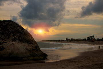 Brazilian beach, corner of the beach with big rock, sand and sea bathing the sand, curve of the beach with the sunset, leaving the golden image