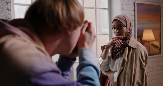 Beautiful young muslim model wearing makeup and traditional hijab head scarf posing for camera man taking photos, presenting new clothing collection - beauty, fashion concept 4k footage