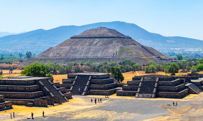 The majestic Sun Pyramid with a few unrecognizable tourists and minor temples in Teotihuacan,...