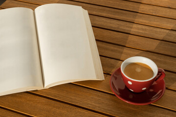 Blank book and coffee cup on a wooden table. Disconnection moment. Tranquility and relaxation.