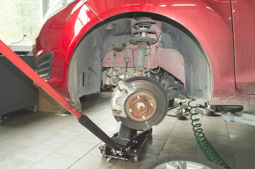 Front suspension of a red car mounted on a lift