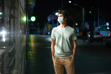 Handsome young man with face mask walks looking at empty shelves in a shop on city street at night