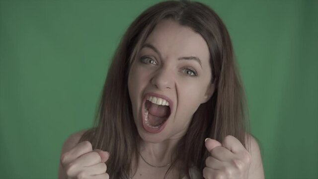 Young angry girl is screaming. Depressed, stressed beauty woman is in disappointment. Shouting female on green screen, mock up, chroma key.