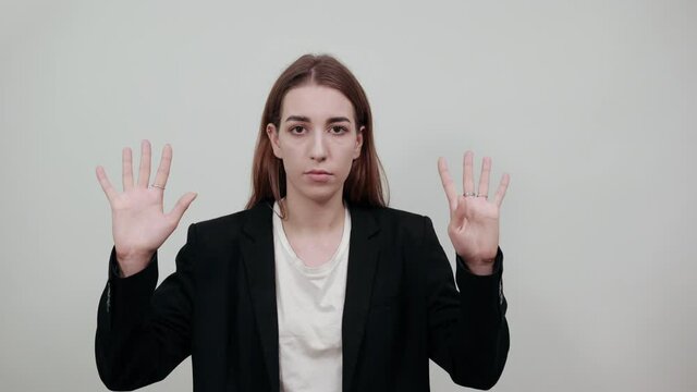 Showing nine 9 fingers hand gesture, show the number three with hands, pointing up arm while smiling confident, happy. Young attractive woman with brown hair in a light t-shirt and black jacket