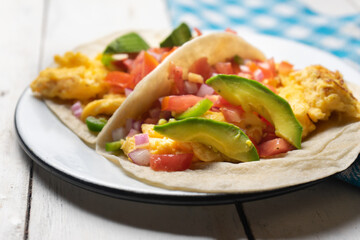 Breakfast egg tacos with flour tortilla and fresh sauce on white background