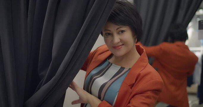 portrait of a woman peeping from a fitting room and looking at the camera